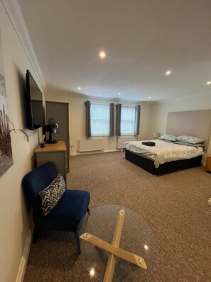 A bedroom with a bed, a desk, a chair, a TV, and a window with curtains. - Spacious and comfortable town house close to the beach and town! (Bournemouth)