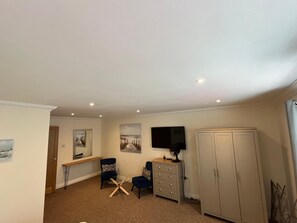 A room with a desk, two chairs, a television, a wardrobe, and a door. - Spacious and comfortable town house close to the beach and town! (Bournemouth)