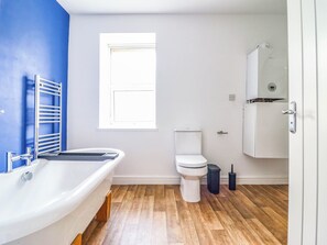 A bathroom with a bathtub, toilet, and a window. - Flat 4 Greenfields (Barmouth)