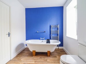 A bathroom with a clawfoot bathtub, a white toilet, and a window. - Flat 4 Greenfields (Barmouth)
