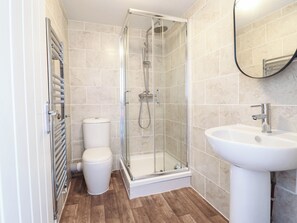 A modern bathroom with a glass-enclosed shower, a white toilet, and a sink. - Flat 4 Greenfields (Barmouth)