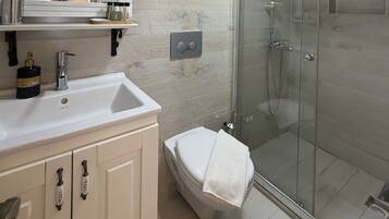 A bathroom with a white sink, a toilet, and a glass shower enclosure.