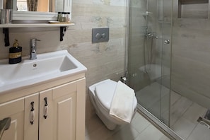 Een badkamer met een wit wastafelmeubel, toilet en een douchecabine van glas.