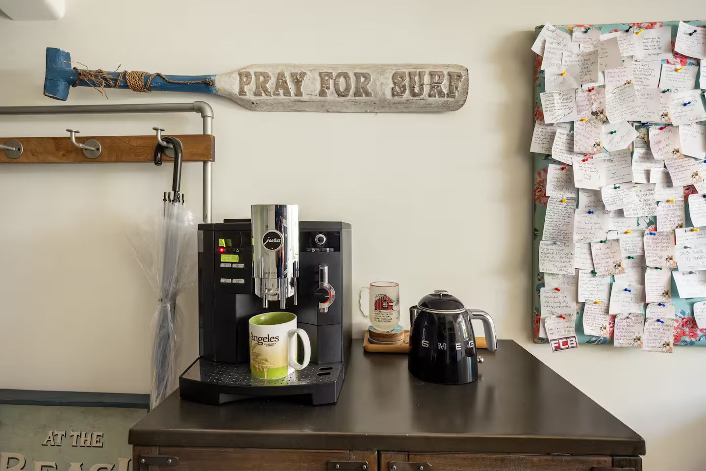 A coffee machine, a mug, a kettle, a sign, and a bulletin board with notes.