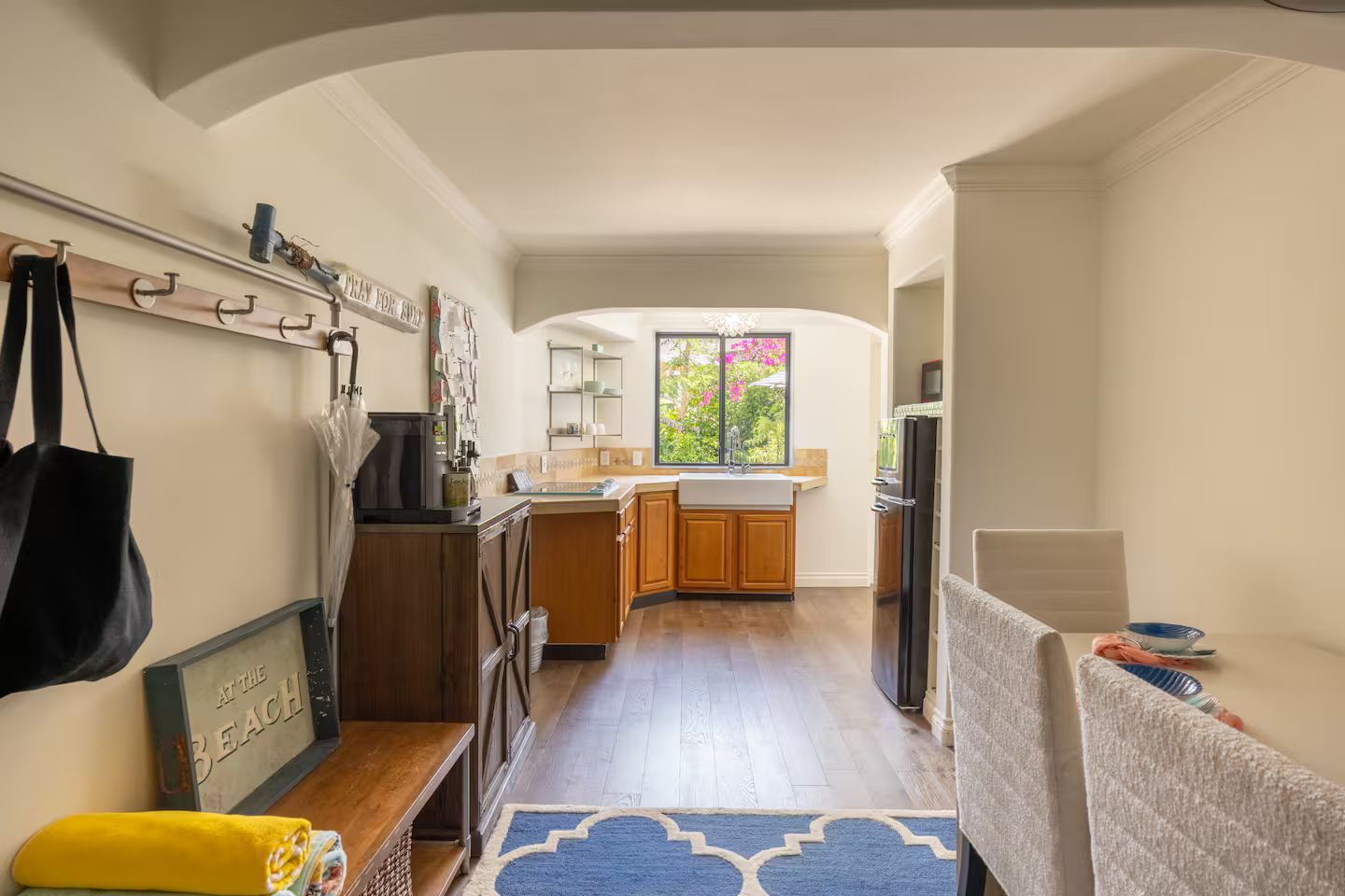 A compact kitchen with wooden cabinets, a built-in sink, and a window offering a view of greenery.