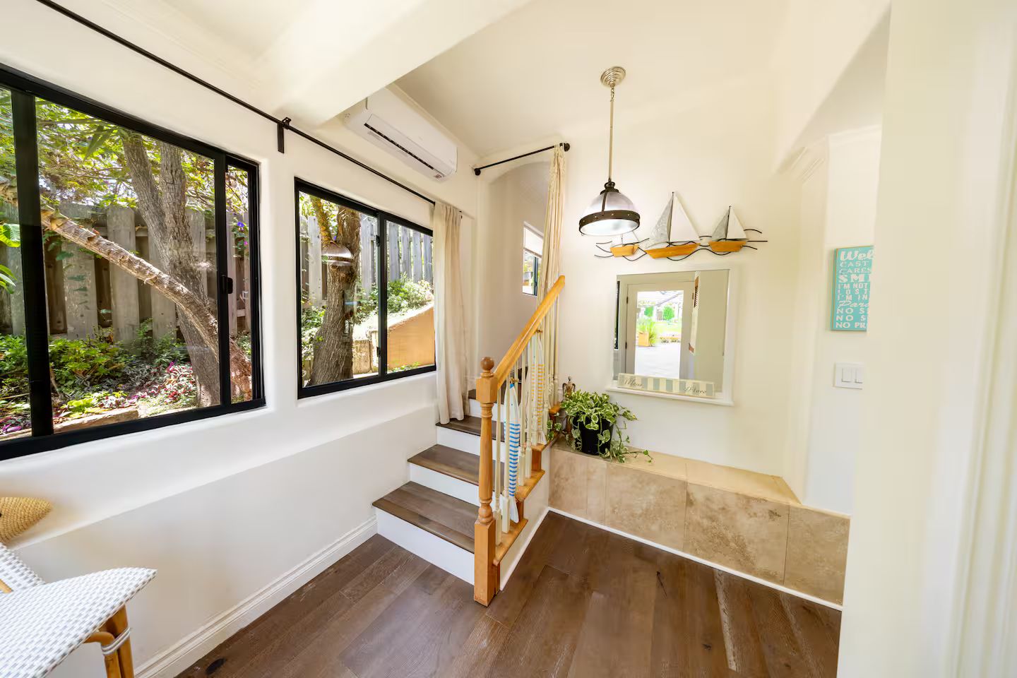 A staircase with wooden steps and a handrail, leading to a landing with a mirror and a potted plant.