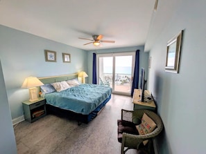 A hotel room with a bed, two bedside lamps, a ceiling fan, a desk with a computer, a chair, and a view of the ocean through a sliding door. - Laketown Wharf 907-pcb Ocean View Oasis (Panama City Beach)