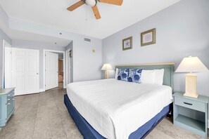 Ein Schlafzimmer mit einem Bett, zwei Nachttischlampen, einem Deckenventilator und einer Tür zu einem anderen Raum.