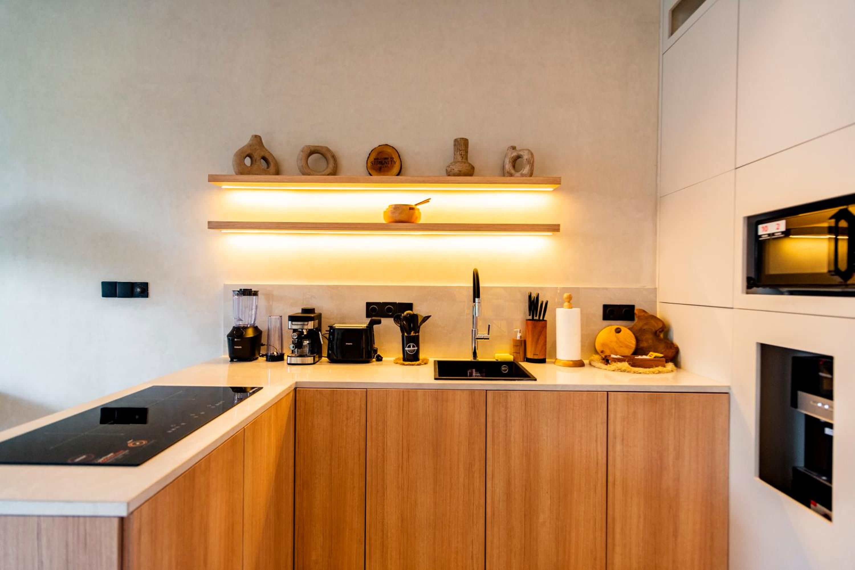 Una cocina moderna con horno empotrado, cafetera, tostadora y pileta.