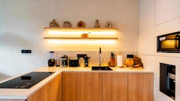 Una cocina moderna con horno empotrado, cafetera, tostadora y pileta.