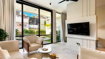 Una sala moderna con televisor de pantalla plana, asientos cómodos y vistas a una piscina y edificios.