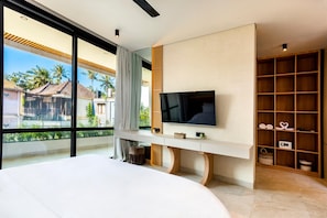 Quarto moderno com uma cama grande, uma TV presa a um console branco e vista para palmeiras através de amplas janelas.