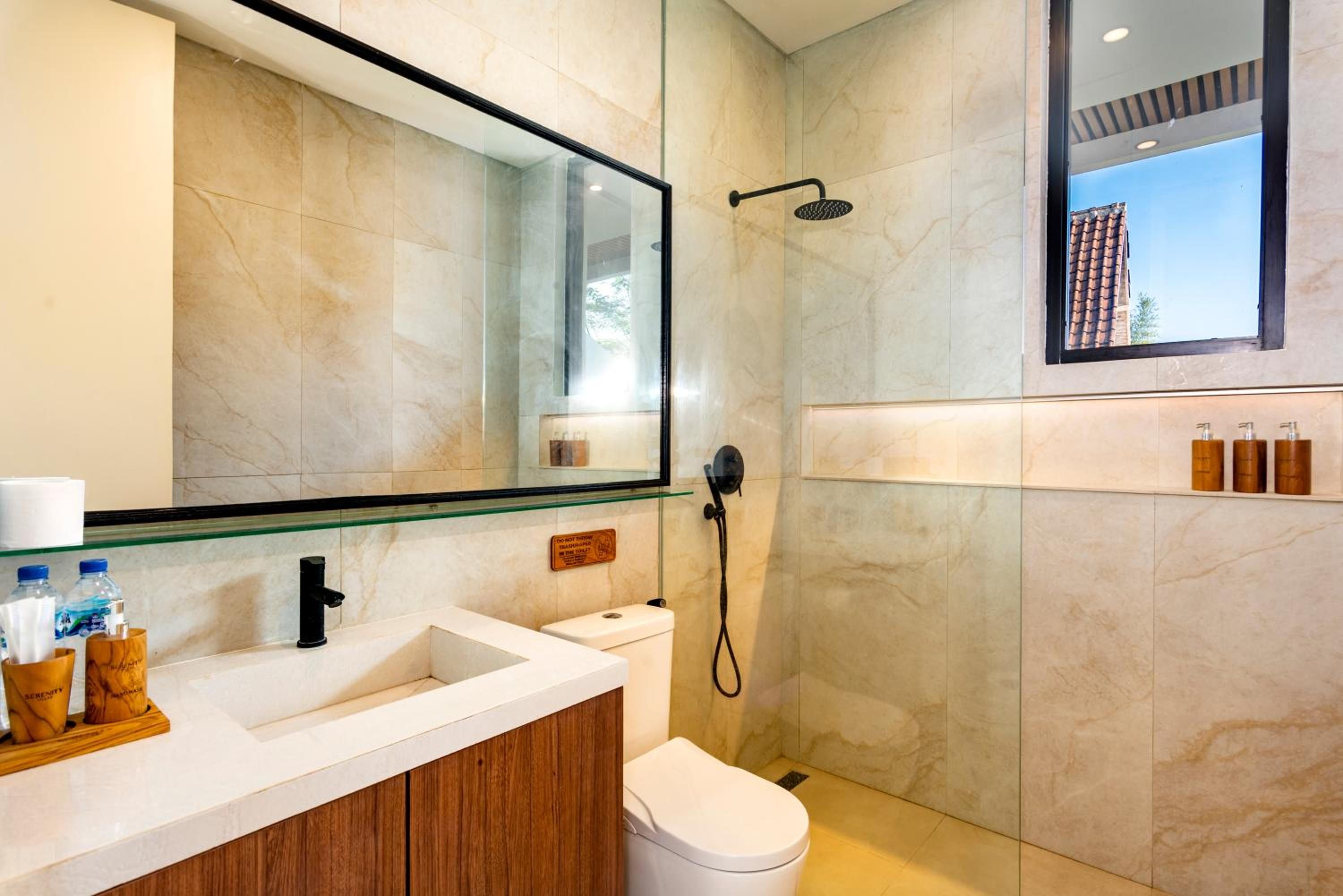 A modern bathroom with a glass shower enclosure, a white sink, and a toilet.