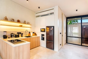 Cozinha moderna com ilha central, eletrodomésticos embutidos e uma ampla porta de vidro deslizante para área externa.