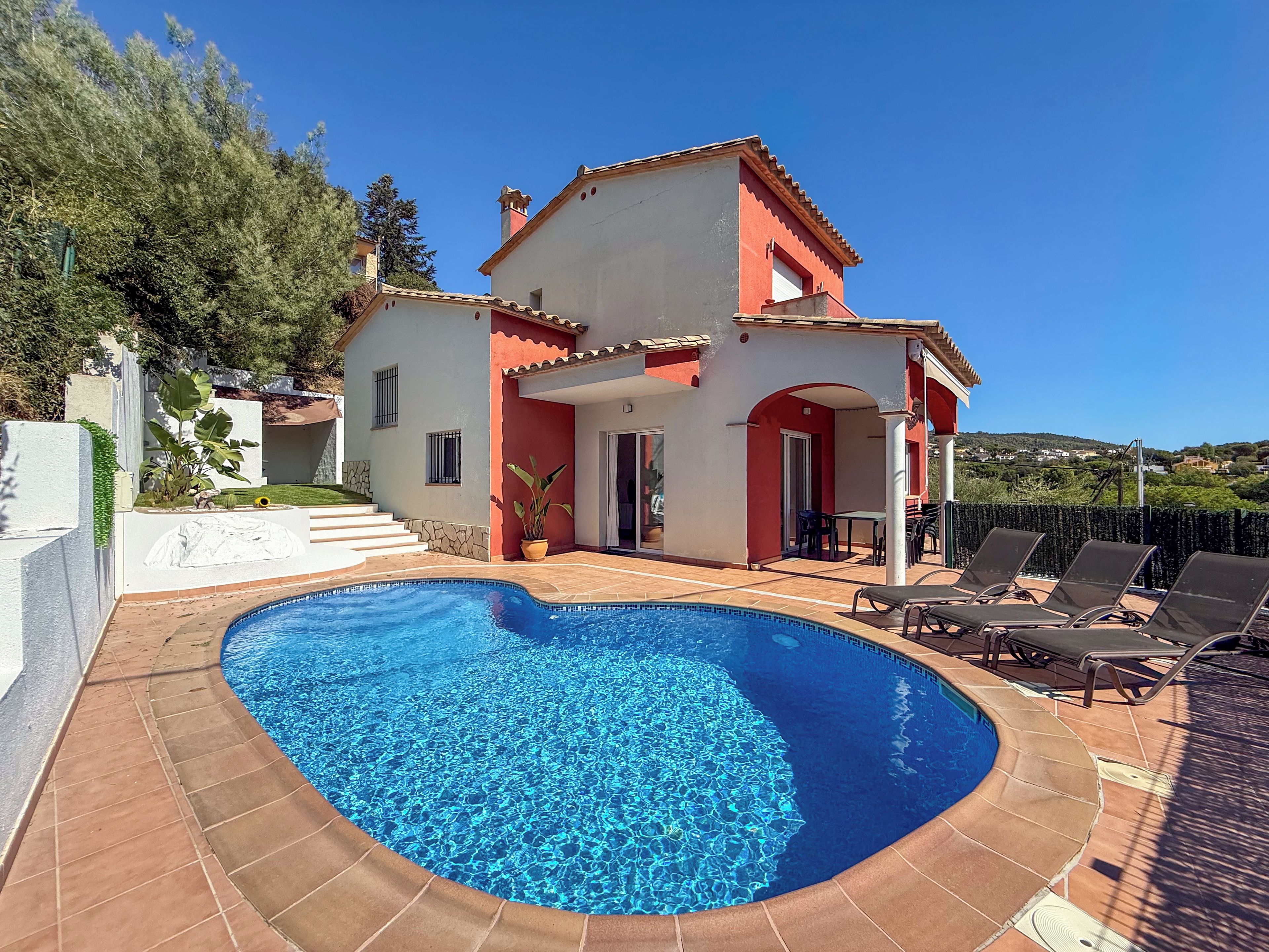 A two-story house with a swimming pool and outdoor seating area.