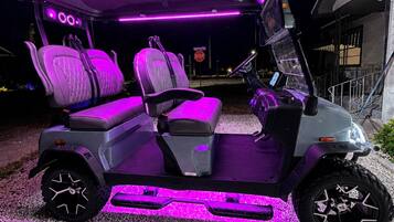 A golf cart with purple LED lighting on the seats and undercarriage.