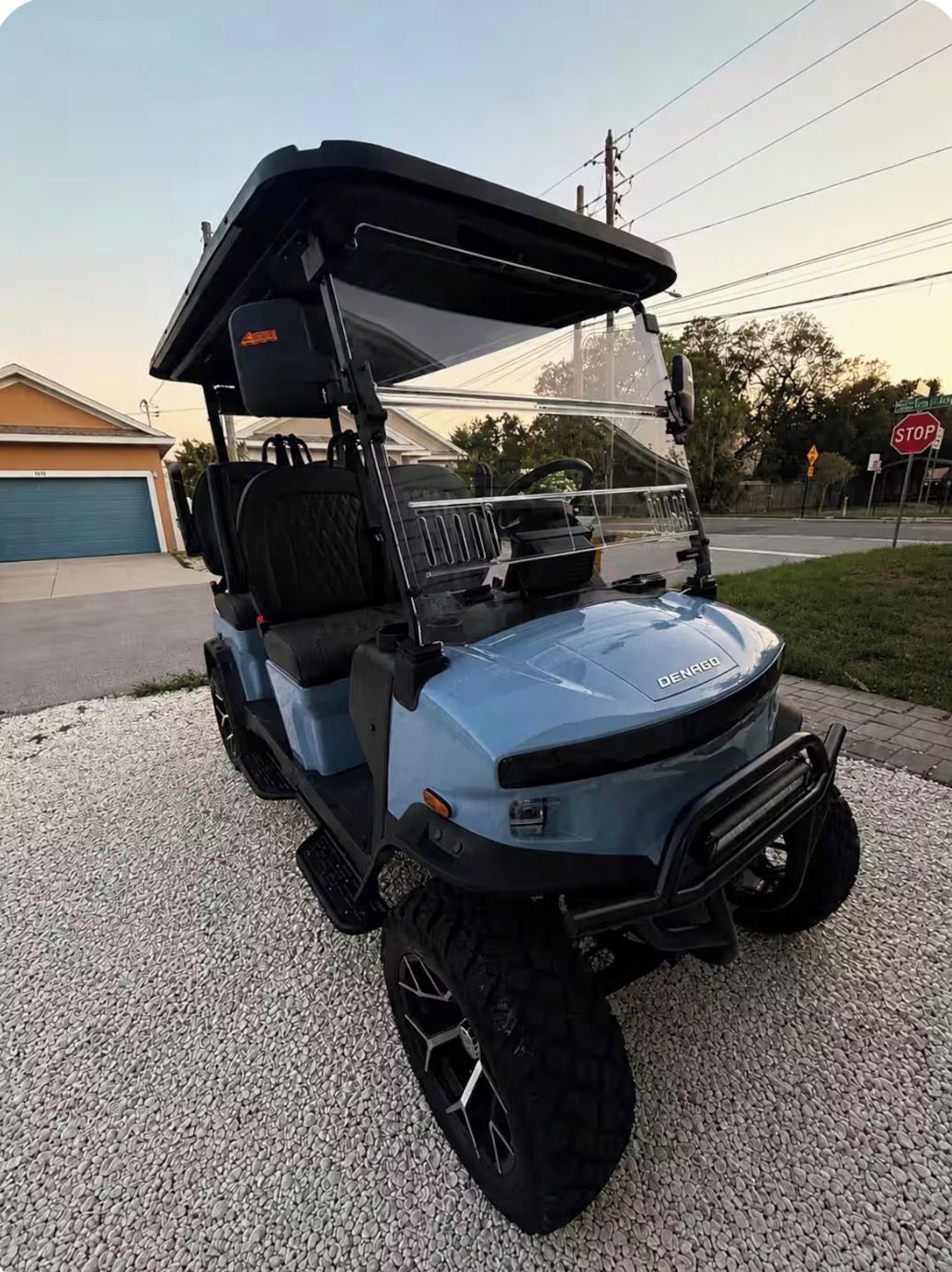 A golf cart parked on a gravel driveway with a garage in the background.