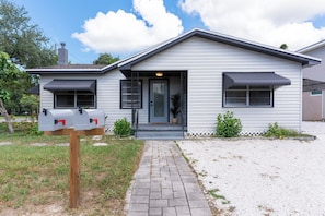 A single-story house with a front porch, a mailbox, and a small garden area.