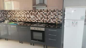 Eine Küche mit Gasherd, Backofen und einem weißen Kühlschrank.