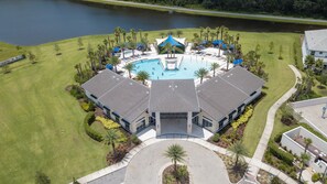 An aerial view of a resort with a central swimming pool, multiple lounge areas, and a large building with a distinctive roof. - The best 9-suite house at Sonoma Resort (Kissimmee)