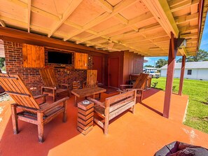 Un patio exterior con muebles de madera, un muro de ladrillo y un televisor.