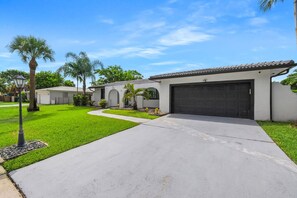 A residential area with a paved driveway leading to a house with a garage. - Pelican Point Waterfront Heated Pool Tiki (Plantation)