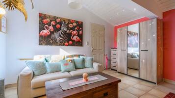 Un salon avec un canapé, une table basse et un tableau représentant des flamants roses et un zèbre.
