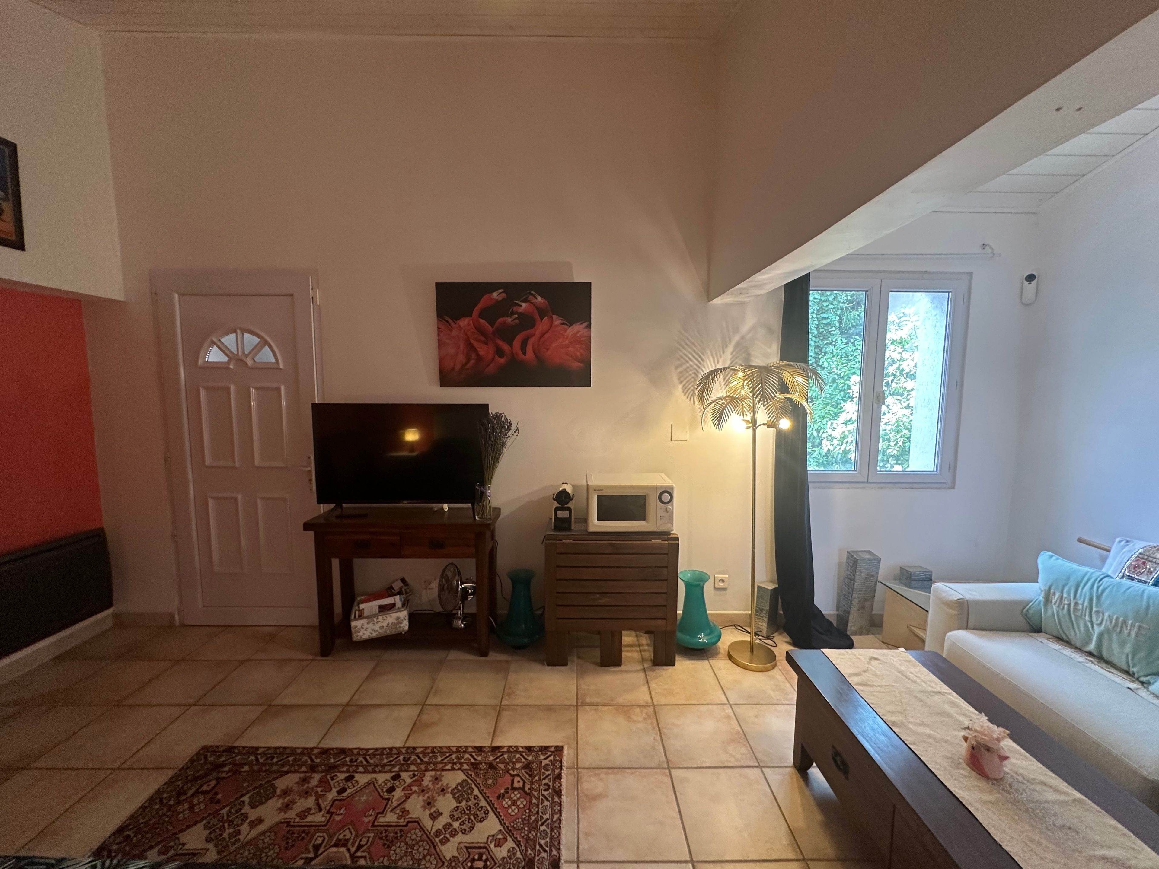 Un salon équipé d’une télévision, d’un four à micro-ondes, d’une petite table, d’un canapé et d’une fenêtre donnant sur un beau paysage.