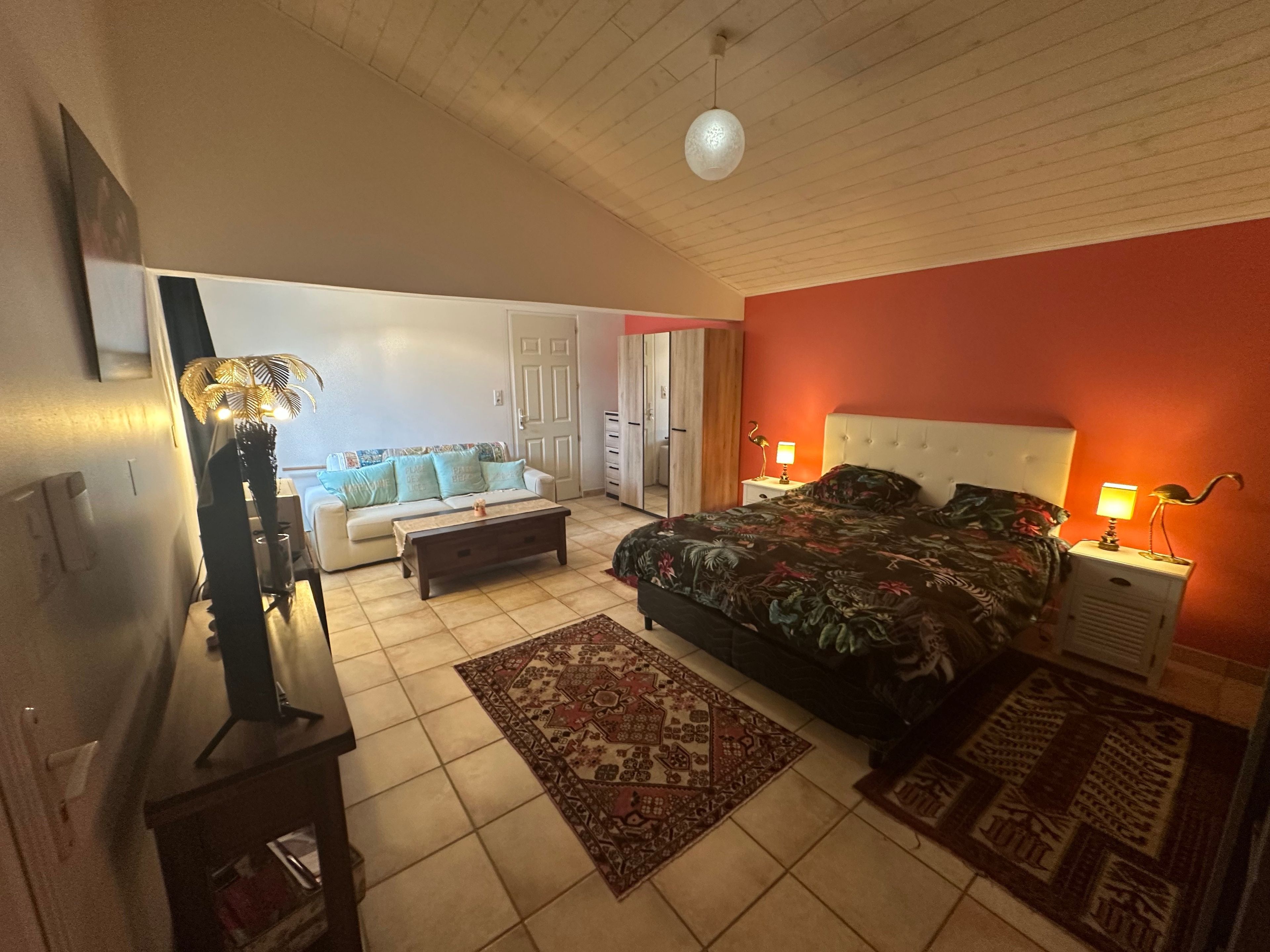 Ein Schlafzimmer mit einem Bett, Nachttischen, einem Sofa und einem Spiegel.