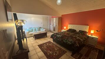 Ein Schlafzimmer mit einem Bett, Nachttischen, einem Sofa und einem Spiegel.