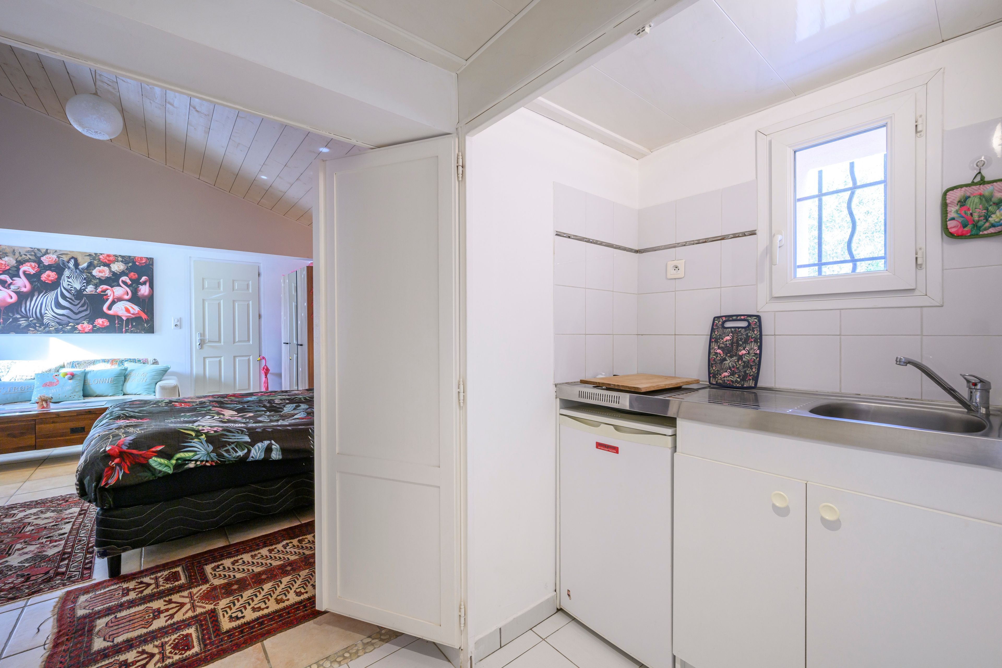 A compact kitchen with white cabinets, a window, and a sink.