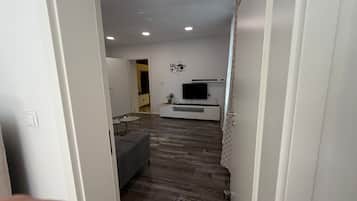A modern living room with a sofa, a TV, and a coffee-themed wall decoration.