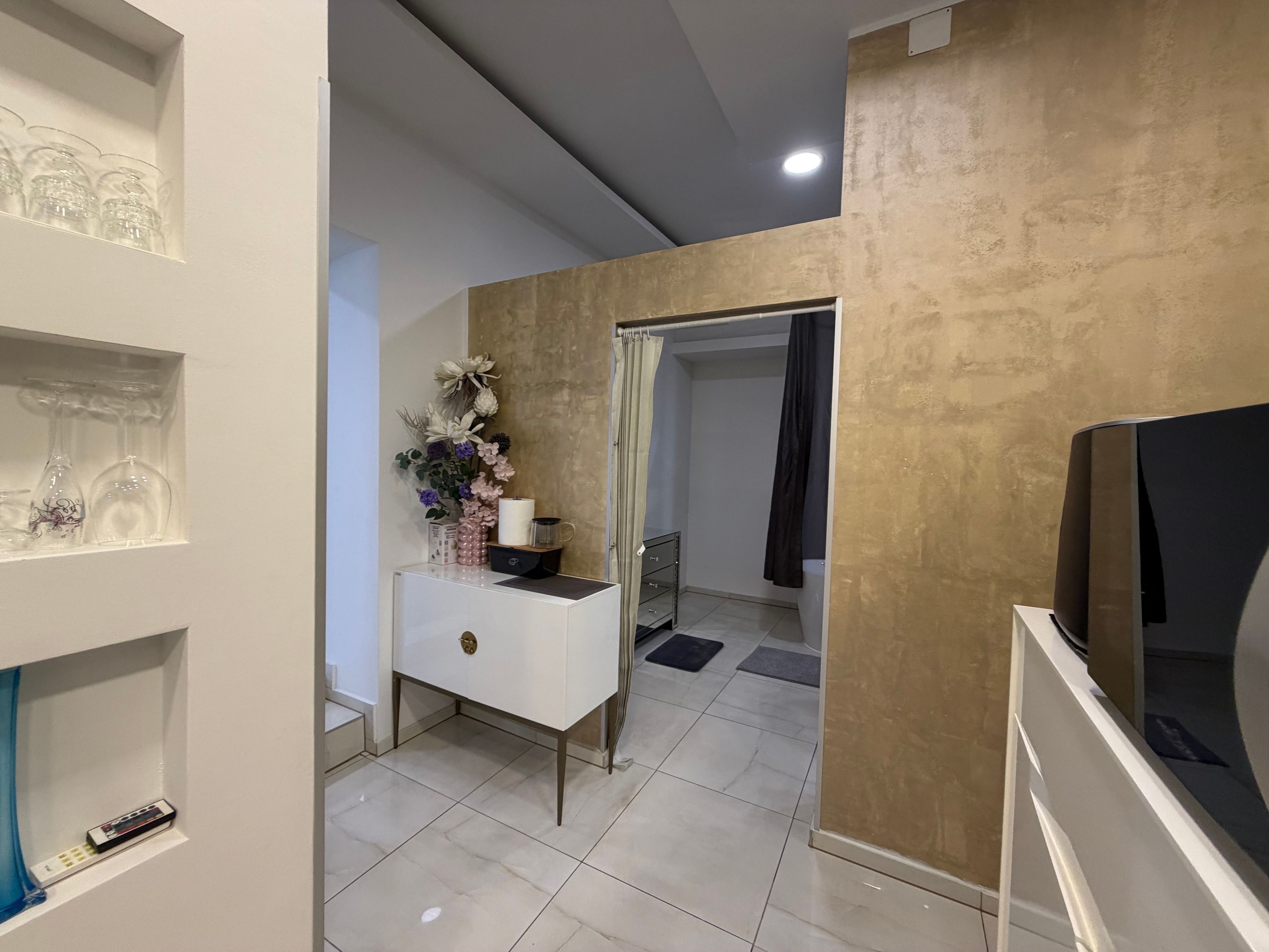 A modern living room with a white console table, a TV, and a glass cabinet with decorative items.
