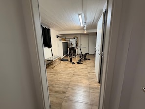 Una habitación con cama, equipo de ejercicio, un radiador y una puerta que da a otra habitación.