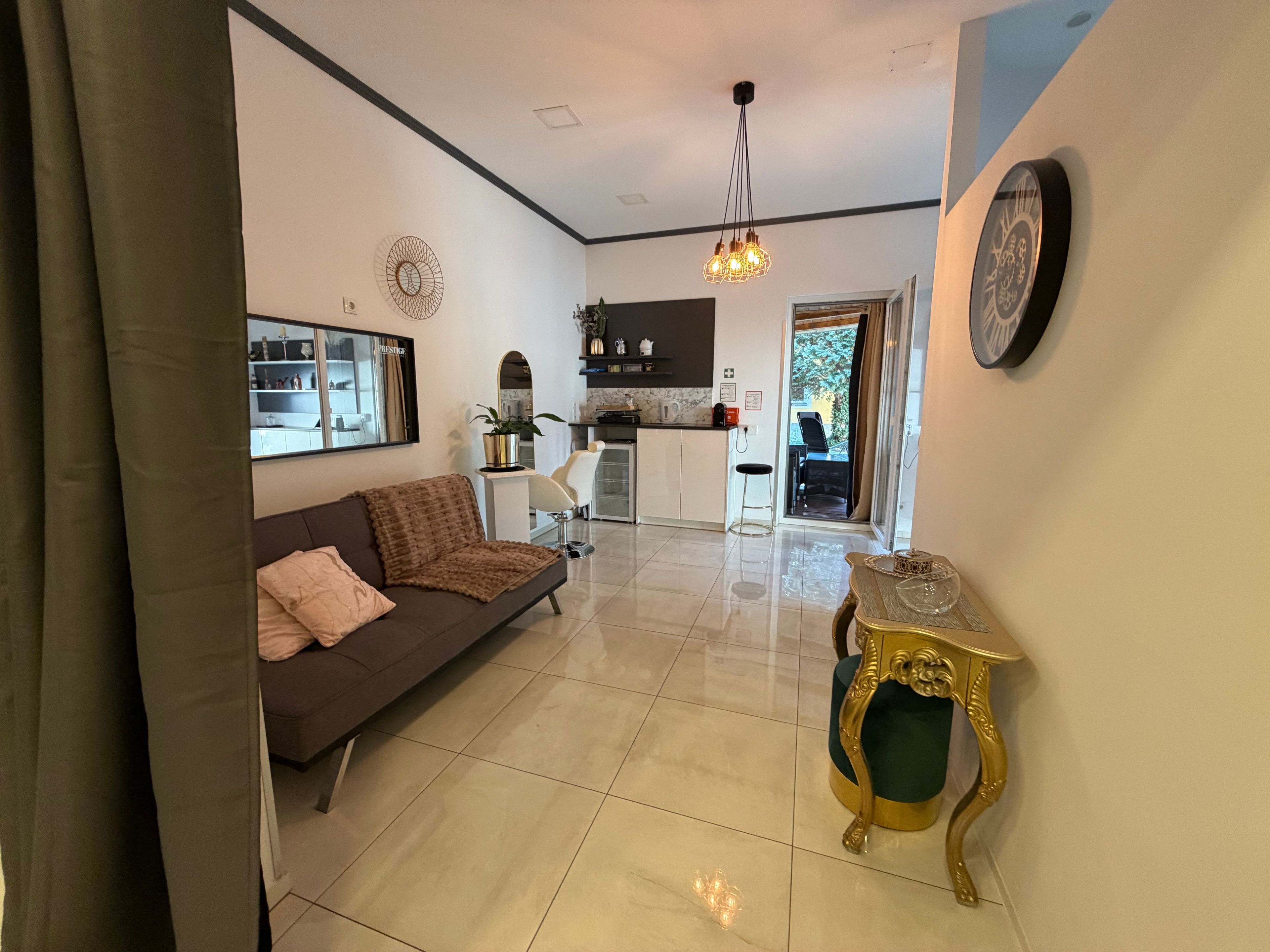 A modern living room with a sofa, a decorative table, and a kitchen in the background.