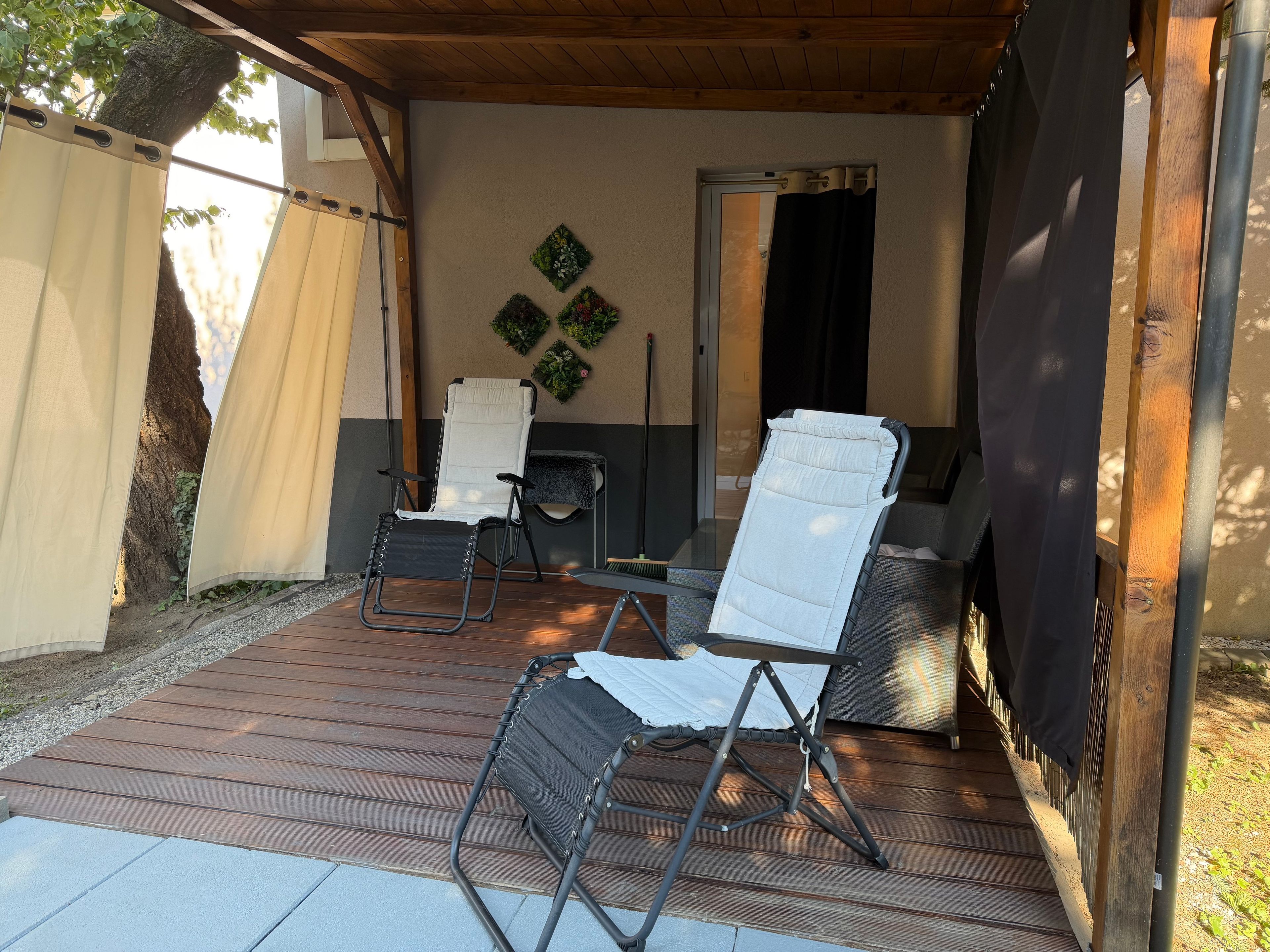 An outdoor patio with two folding chairs, a table, and a grill.