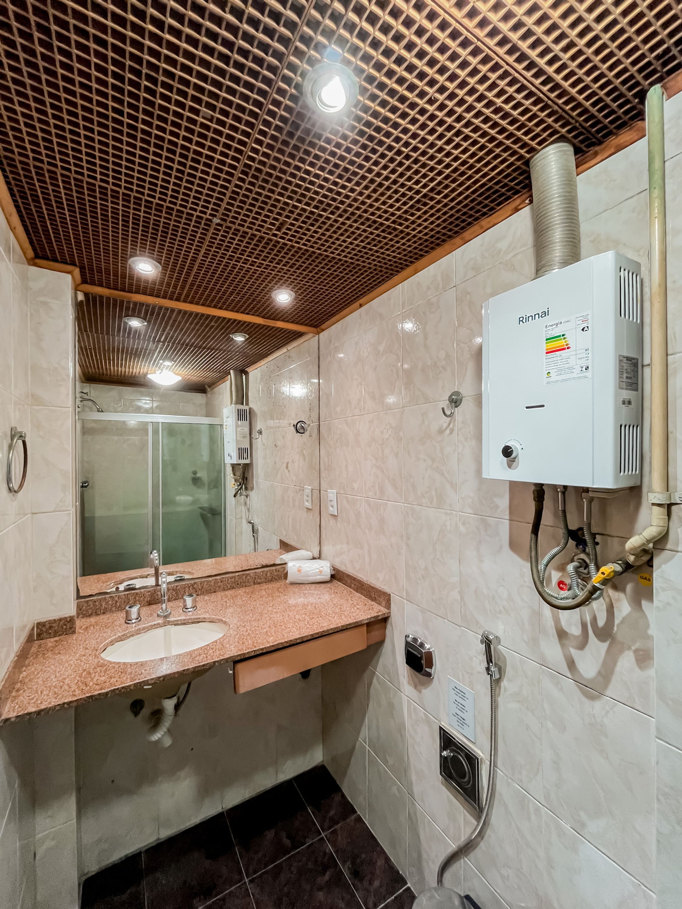 Een moderne badkamer met een douche, een wastafel met spiegel en een wandradiator.