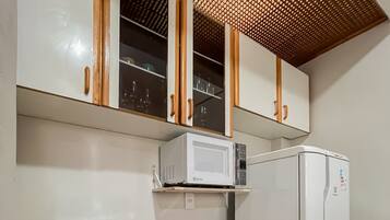 A compact kitchen with a gas stove, a microwave, and a refrigerator.