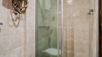 A bathroom with a toilet, a glass-enclosed shower, and a water heater mounted on the wall.