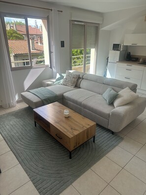 A living room with a sofa, a coffee table, and a view of the outside. - Cozy Apartment Near Valence (Bourg-lès-Valence)