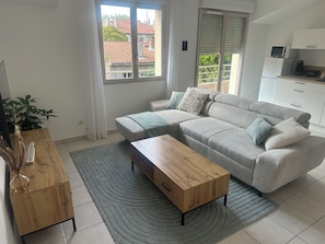 A modern living room with a sofa, a wooden coffee table, and a view of the outside. - Cozy Apartment Near Valence (Bourg-lès-Valence)