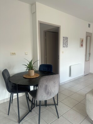 A dining area with a round table, two chairs, a potted plant, and a blue chair. - Cozy Apartment Near Valence (Bourg-lès-Valence)