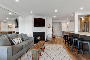 Ein modernes Wohnzimmer mit Kamin, einer Couch, einem Couchtisch und einer Küchenzeile mit Bar.
