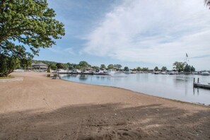 Un port de plaisance avec des bateaux amarrés, une plage de sable et un bâtiment doté d’un toit en pente.