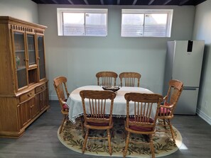 A dining room with a round table, six wooden chairs, a floral rug, a wooden cabinet, and a refrigerator. - Spacious 2 bedroom Guest suite 9 feet ceiling, 85 inch tv, ping pong kitchen Gym (Oakville)