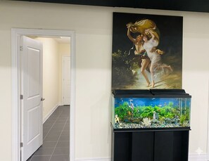 A hallway with a fish tank and a painting on the wall. - Spacious 2 bedroom Guest suite 9 feet ceiling, 85 inch tv, ping pong kitchen Gym (Oakville)