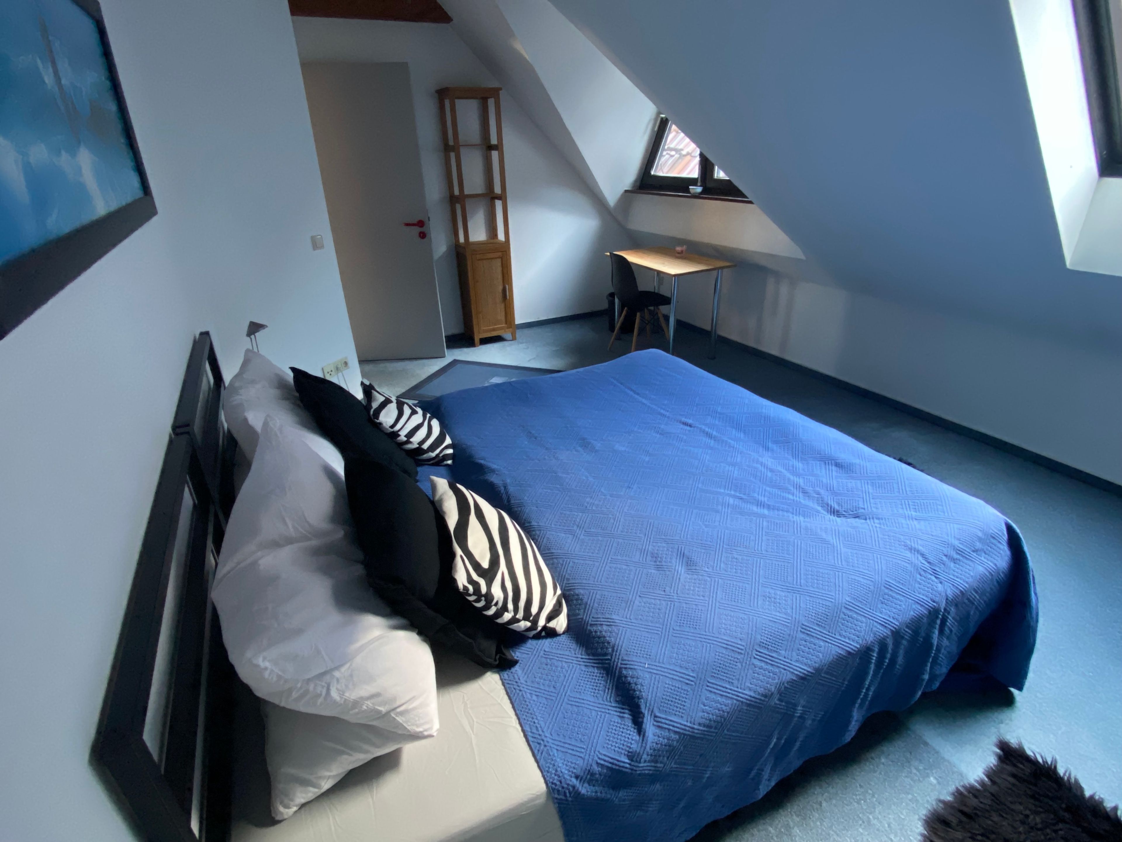 A bedroom with a bed, pillows, a desk, and a chair.