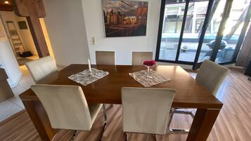 A dining area with a wooden table, six chairs, a candle, and a vase with flowers.