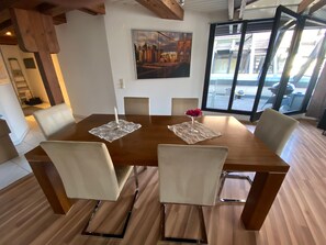 Un comedor con una mesa de madera, seis sillas, una vela y un florero con flores.