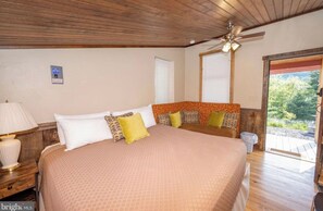 A bedroom with a large bed, a ceiling fan, and a view of the outdoors. - Dream Catcher Cabin #2 · Glamping · Private bath in shared building (Swanton)